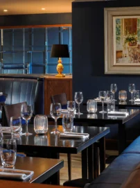 Intimate hotel restaurant with family-style table setting, cosy booth seating and warm lamps