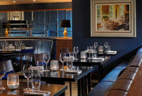 Intimate hotel restaurant with family-style table setting, cosy booth seating and warm lamps