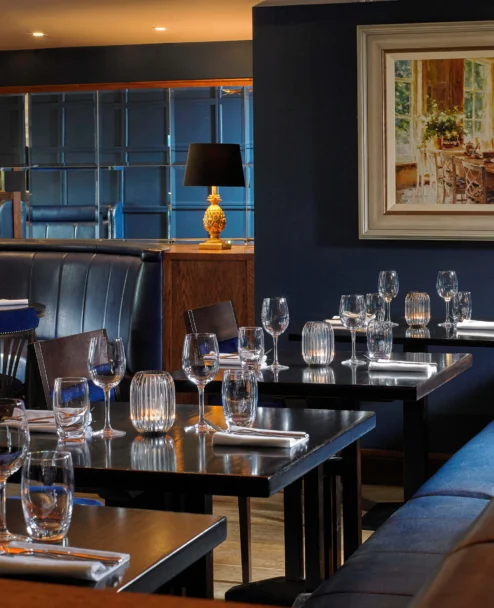Intimate hotel restaurant with family-style table setting, cosy booth seating and warm lamps
