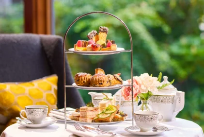 Three-tier afternoon tea with sandwiches, scones and pastries on a cosy hotel table, family setting (no visible text)