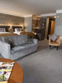 Spacious family hotel suite with two large beds, sofa, seating area and fresh flowers, warm lighting