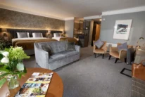 Spacious family hotel suite with two large beds, sofa, seating area and fresh flowers, warm lighting