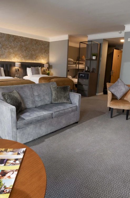Spacious family hotel suite with two large beds, sofa, seating area and fresh flowers, warm lighting