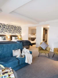 Spacious family suite with two double beds, bunk beds, sofas and cosy seating in warm décor