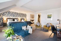 Spacious family suite with two double beds, bunk beds, sofas and cosy seating in warm décor