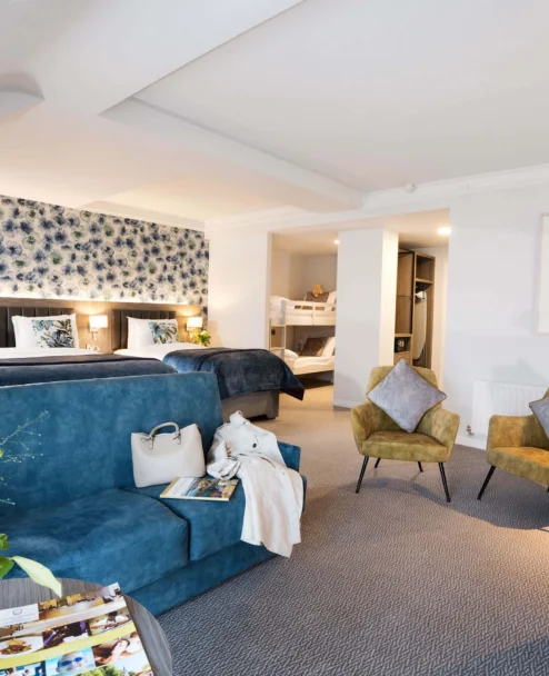 Spacious family suite with two double beds, bunk beds, sofas and cosy seating in warm décor