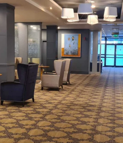 Spacious hotel lounge with a family relaxing in armchairs by tables, warm lighting, patterned carpet (no visible text)