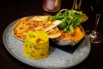 Warm family-style meal with flatbread, spiced couscous and curry served on a plate, cosy dining setting