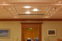 Family-style group seated at a conference table beyond a warm hotel lounge entrance, chairs and soft lighting