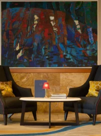 Cosy lounge seating for two with cushions, small table, lamp and abstract wall art in a hotel lobby