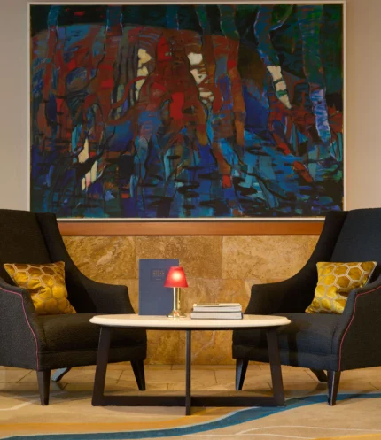 Cosy lounge seating for two with cushions, small table, lamp and abstract wall art in a hotel lobby