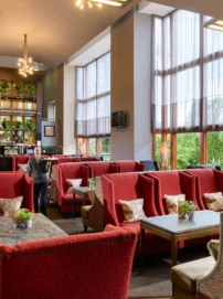 Family enjoying relaxed lounge seating in a bright hotel lobby with large windows and plants