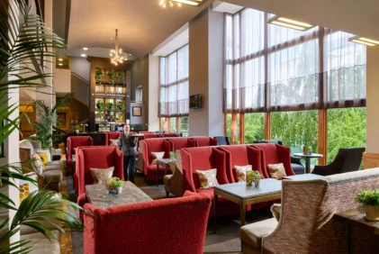 Family enjoying relaxed lounge seating in a bright hotel lobby with large windows and plants