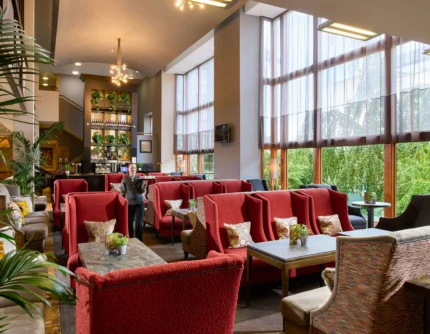 Family enjoying relaxed lounge seating in a bright hotel lobby with large windows and plants