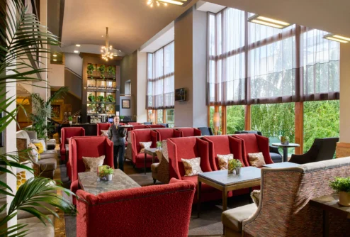 Family enjoying relaxed lounge seating in a bright hotel lobby with large windows and plants