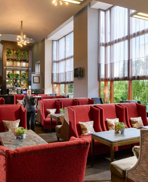 Family enjoying relaxed lounge seating in a bright hotel lobby with large windows and plants