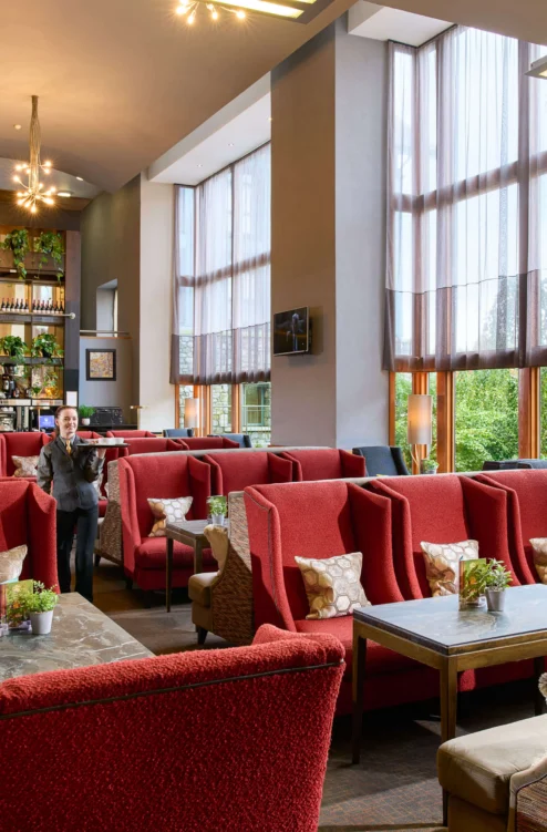 Family enjoying relaxed lounge seating in a bright hotel lobby with large windows and plants