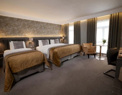 Family-friendly twin room with two cosy beds, seating area and soft natural light, hotel