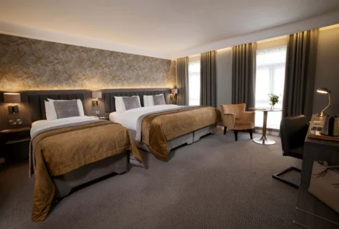Family-friendly twin room with two cosy beds, seating area and soft natural light, hotel