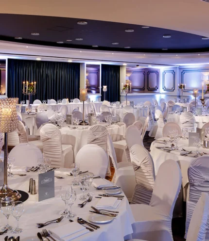 Elegant hotel banquet room set for a family celebration, round tables with white linens, candles and glassware