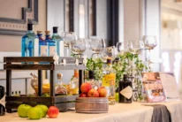 Well-dressed family enjoying drinks at a hotel bar setup with gin bottles, apples and glasses