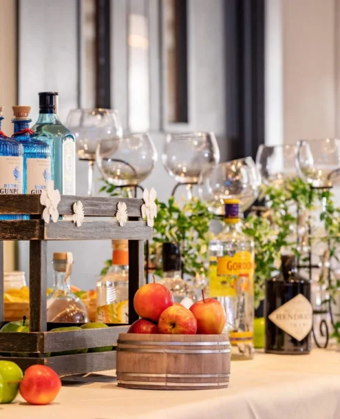 Well-dressed family enjoying drinks at a hotel bar setup with gin bottles, apples and glasses