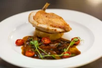 Roasted chicken breast on fondant potato with mushroom sauce and cherry tomatoes, plated fine-dining meal