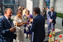 Wedding couple and family sharing champagne outside a modern hotel entrance, bride with bouquet