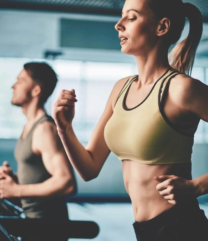 Couple running on treadmills in a bright hotel gym, enjoying a shared workout together, family-friendly