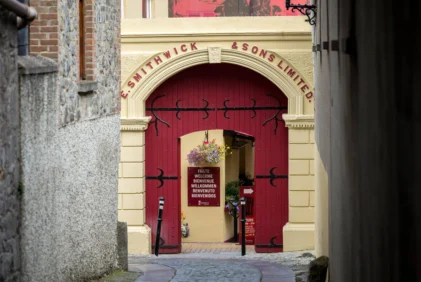Charming family entering a red arched courtyard doorway with welcome sign and hanging flowers