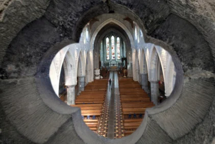 Family exploring a historic church interior, walking down nave past wooden pews and stained glass windows