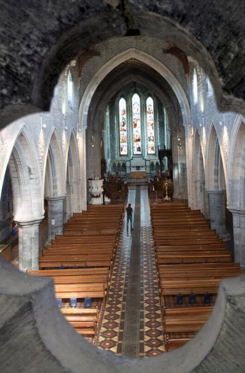 Family exploring a historic church interior, walking down nave past wooden pews and stained glass windows