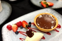 Chocolate tart with cream and fresh berries on a plated dessert at a hotel dining table, family enjoying dessert together