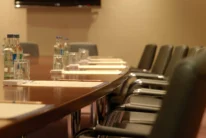 Business family meeting setup in a warm hotel conference room with water, notepads and chairs