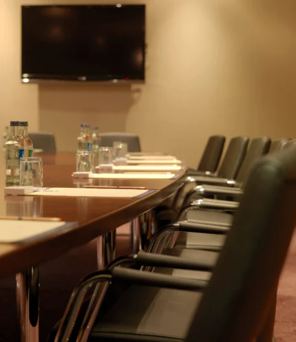 Business family meeting setup in a warm hotel conference room with water, notepads and chairs
