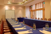 Conference room set for a family meeting with U-shaped tables, notepads, water and projector