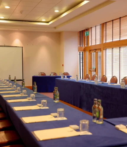 Conference room set for a family meeting with U-shaped tables, notepads, water and projector