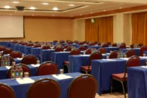 Conference room set for a family or group retreat, rows of tables with notepads, water and projector screen
