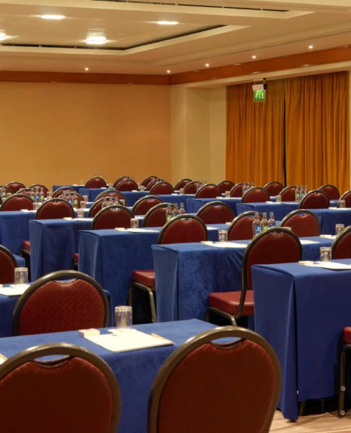 Conference room set for a family or group retreat, rows of tables with notepads, water and projector screen