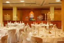 Family celebration in a warm, candlelit hotel banquet room with round tables set for dining