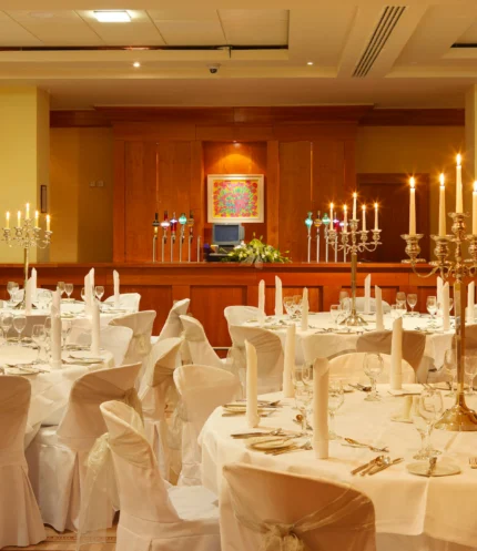Family celebration in a warm, candlelit hotel banquet room with round tables set for dining
