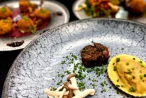 Family-style couple enjoying plated gourmet ravioli, mushrooms and beef in a cosy dining setting (UK)