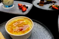Family sharing crème brûlée and desserts on slate plates in a cosy hotel dining setting