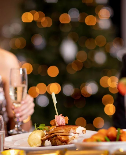 Smiling couple toast with wine at a festive hotel dinner table, warm bokeh lights